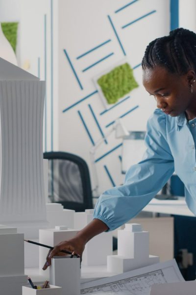 african-american-woman-analyzing-blueprints-plan-building-model-work-architecture-architect-working-with-maquette-layout-print-design-urban-construction-development